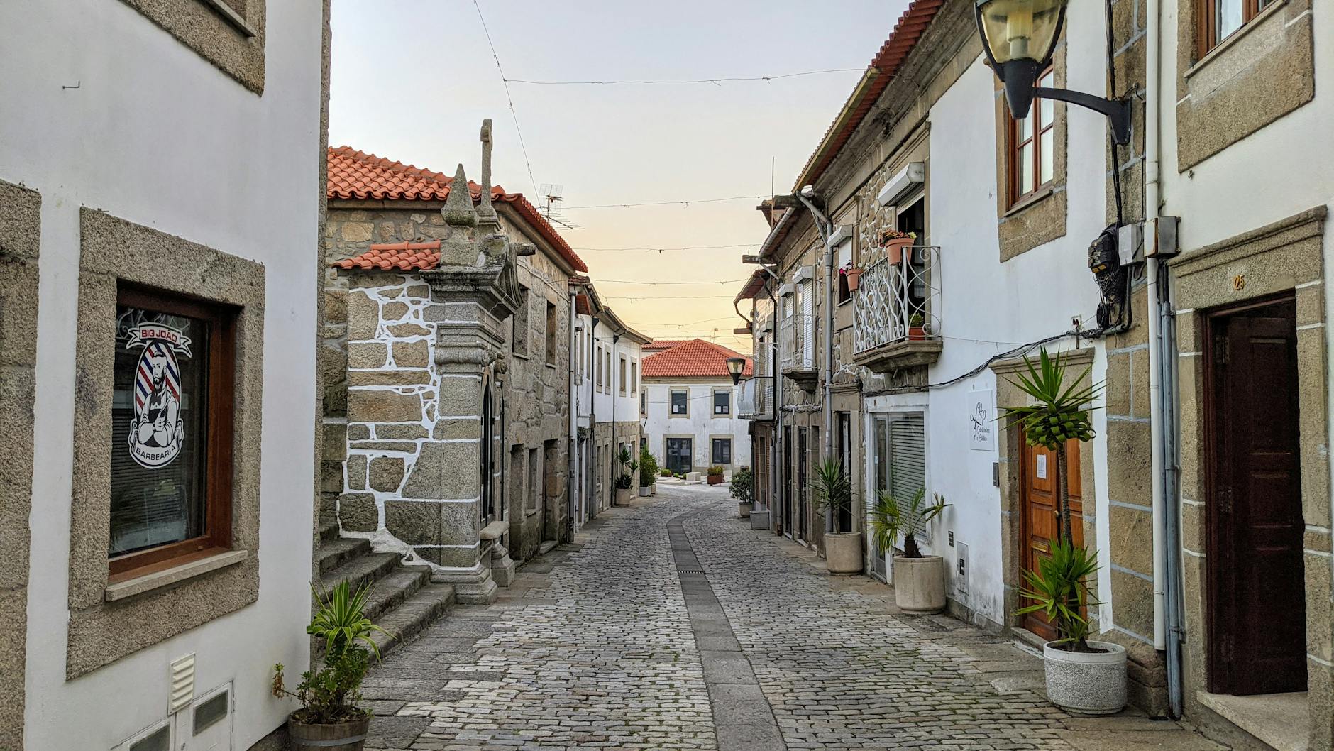 Picturesque cobblestone street in a historic Portuguese village at sunset.